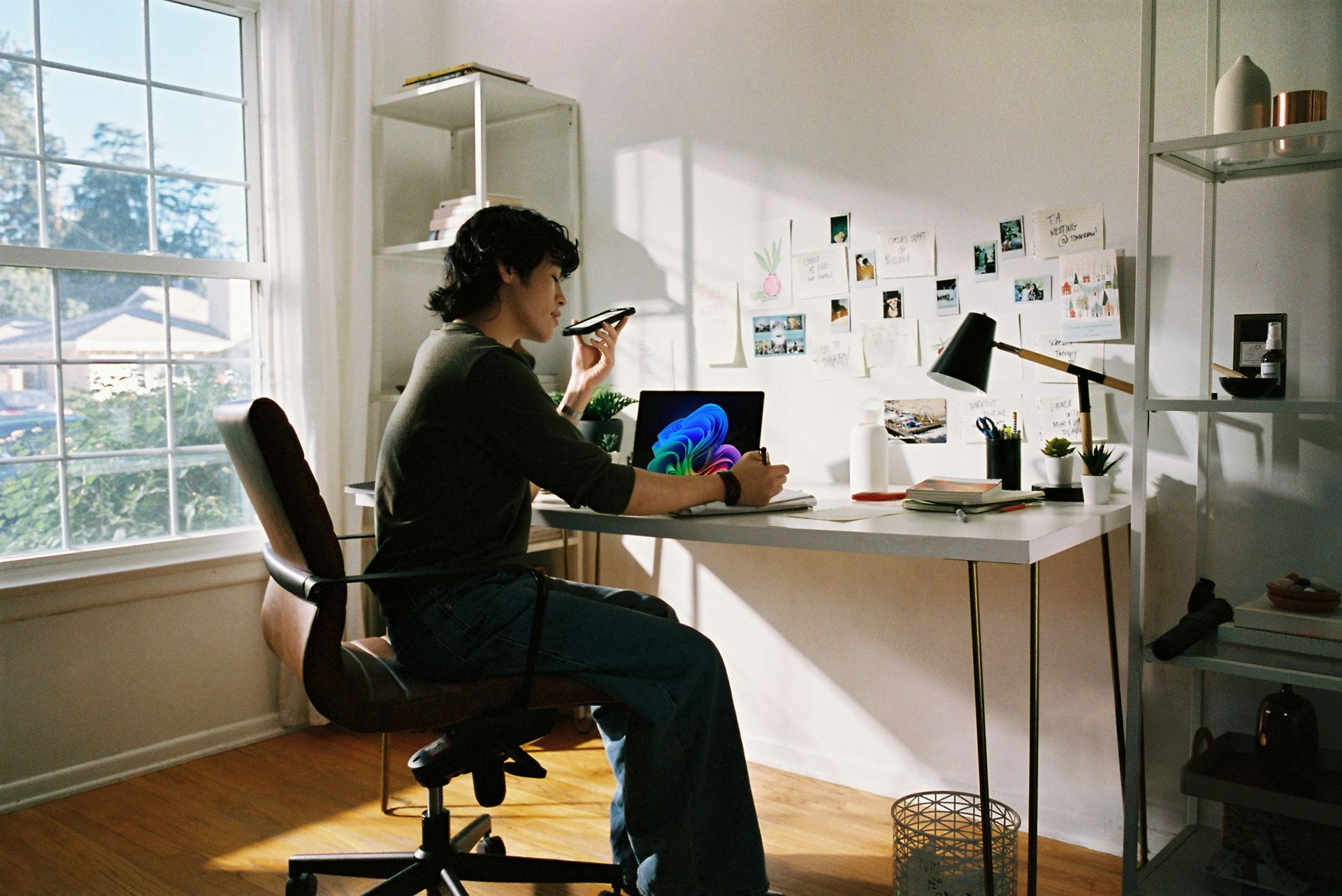 Man on phone in front of desk with laptop